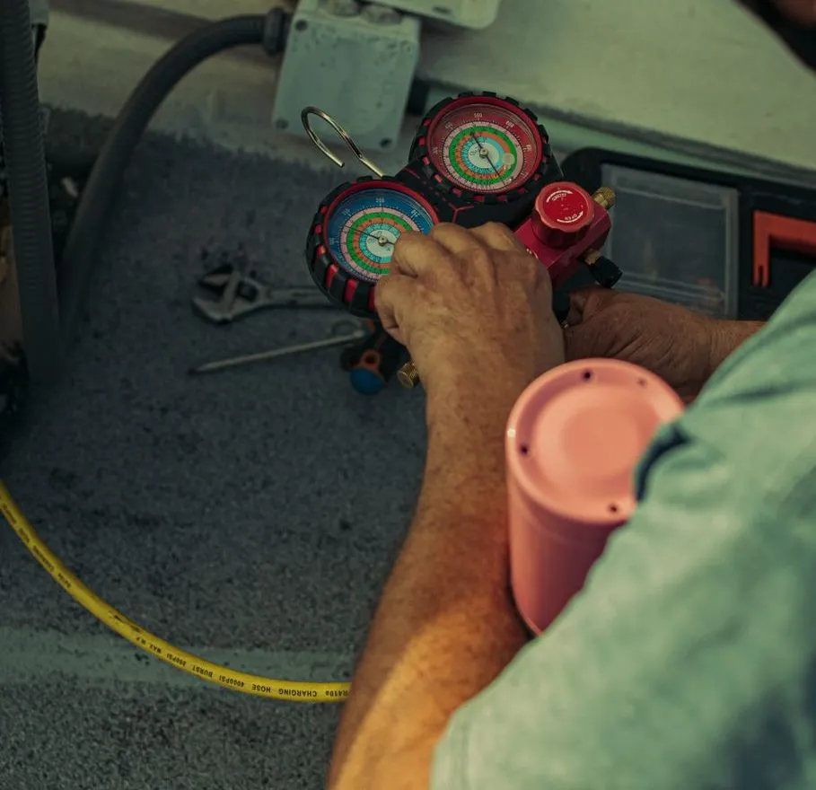 An engineer's hands on a manifold gauge set, reading refrigerant pressures during a service